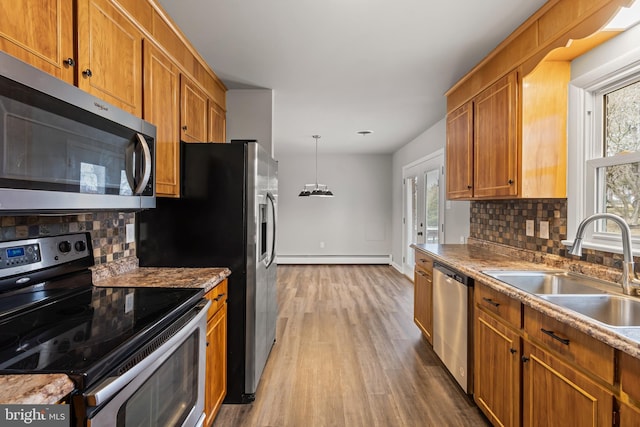 kitchen with a sink, wood finished floors, appliances with stainless steel finishes, and a wealth of natural light