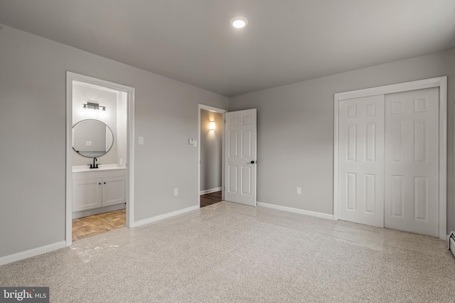 unfurnished bedroom featuring a sink, a closet, baseboards, and ensuite bathroom