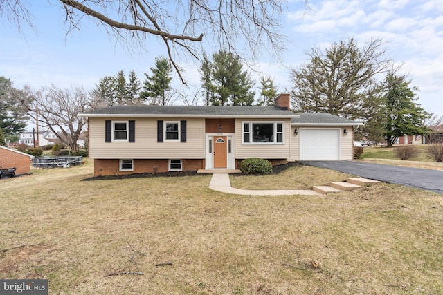 bi-level home featuring aphalt driveway, a front yard, a chimney, and an attached garage