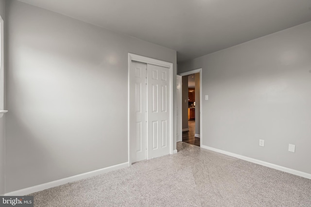 unfurnished bedroom featuring carpet, baseboards, and a closet