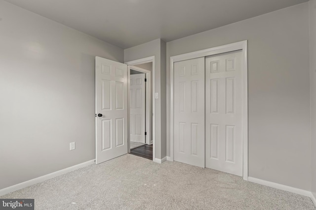 unfurnished bedroom with a closet, carpet flooring, and baseboards