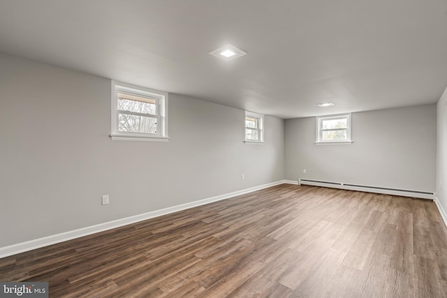 basement with baseboards, baseboard heating, and dark wood-style flooring