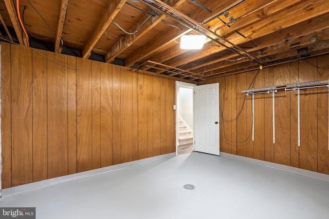 unfinished below grade area featuring wood walls and stairs