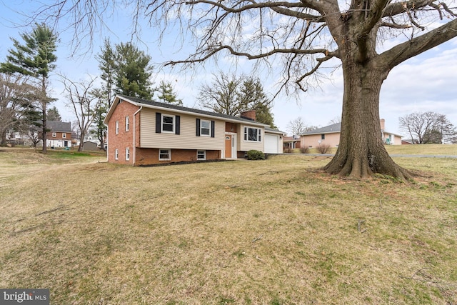 split foyer home with an attached garage, a chimney, and a front lawn