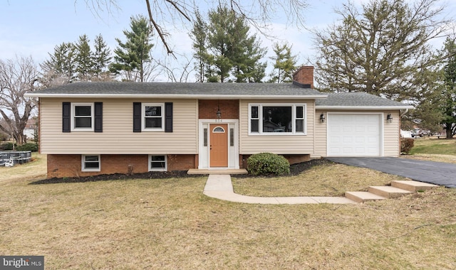 bi-level home with driveway, roof with shingles, a front yard, an attached garage, and a chimney