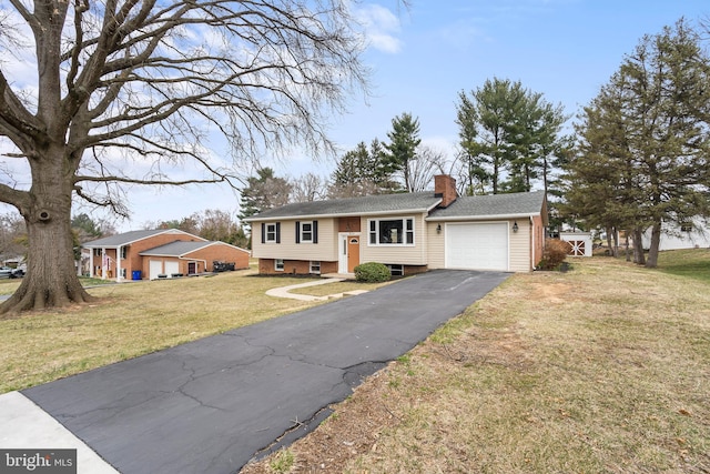 bi-level home with a front yard, an attached garage, driveway, and a chimney