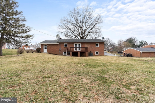 rear view of property with brick siding, a lawn, and french doors