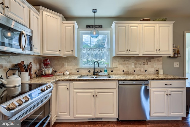 kitchen with white cabinetry, appliances with stainless steel finishes, light stone countertops, and a sink