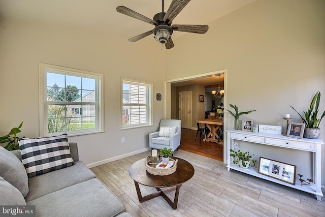 living room featuring ceiling fan with notable chandelier, baseboards, and wood tiled floor