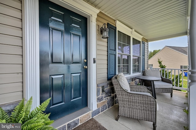 view of exterior entry with stone siding and covered porch