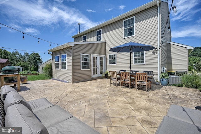 rear view of house with outdoor dining space, french doors, and a patio