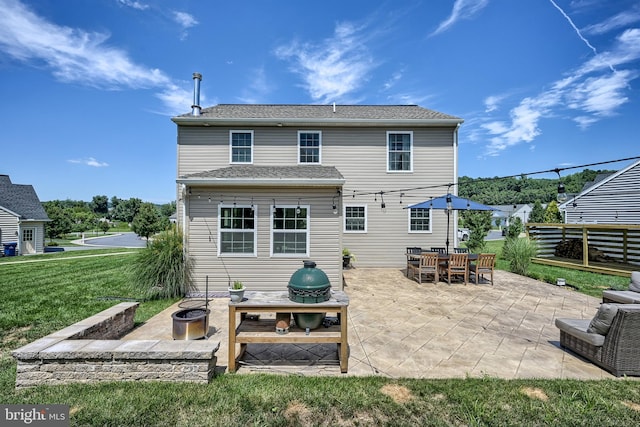 back of property featuring a patio, a yard, fence, and an outdoor fire pit