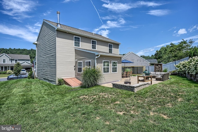 rear view of property featuring a lawn, a patio area, fence, and an outdoor hangout area