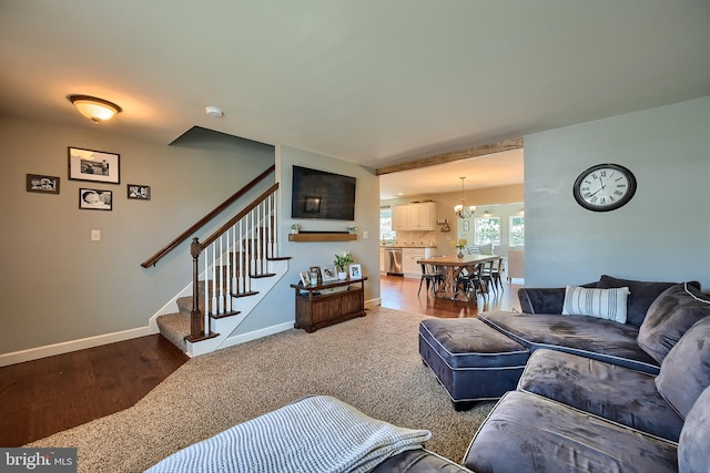 living room featuring stairway, a notable chandelier, wood finished floors, and baseboards