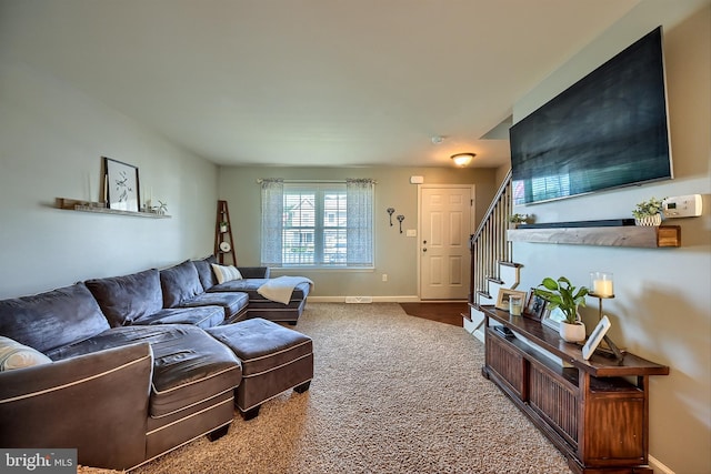 carpeted living area featuring stairway and baseboards