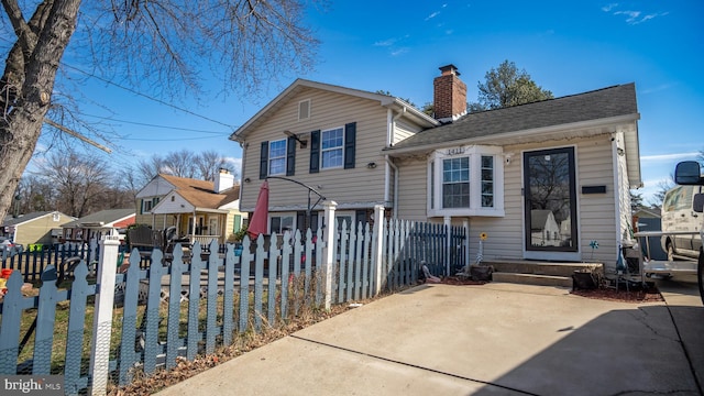 split level home featuring a fenced front yard, a chimney, and entry steps