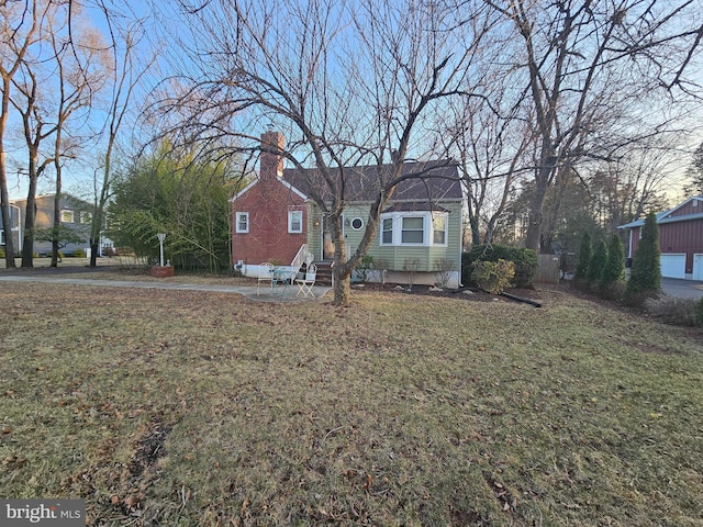 bungalow-style house with entry steps, a chimney, and a front lawn