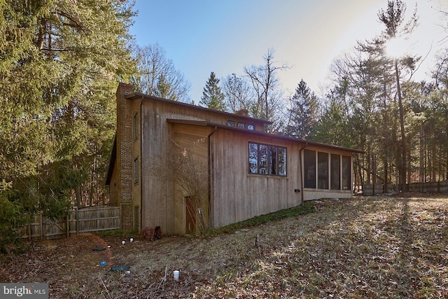 view of outdoor structure featuring fence and a sunroom