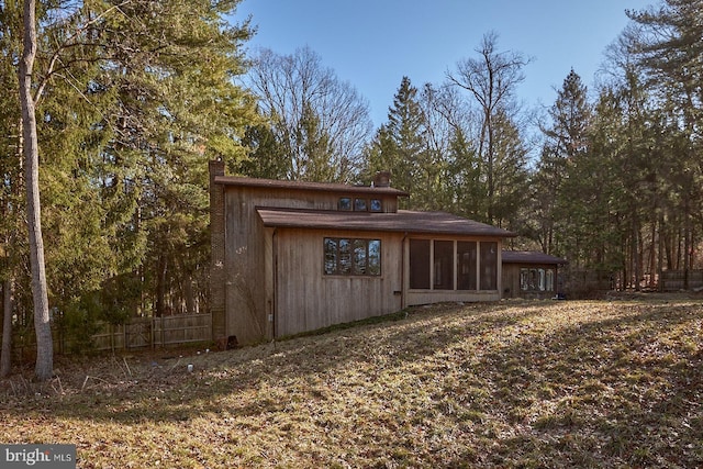 view of outbuilding with fence and a sunroom