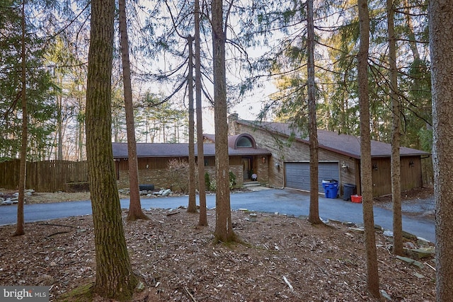 view of front of house with an attached garage, driveway, and fence