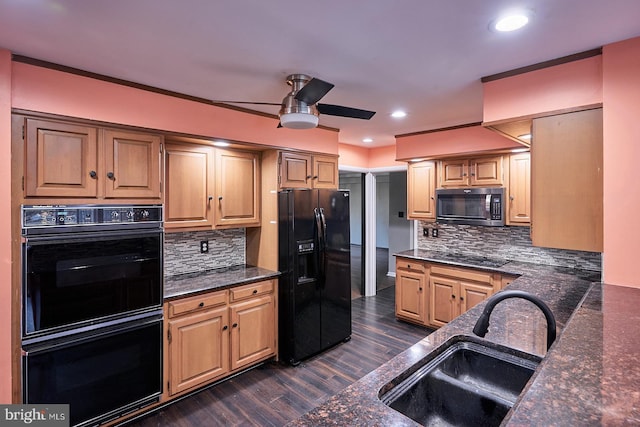 kitchen with a sink, dark wood-type flooring, black appliances, and dark stone countertops