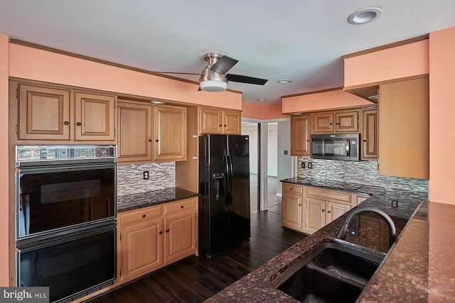 kitchen with black appliances, a sink, dark wood finished floors, dark stone counters, and decorative backsplash