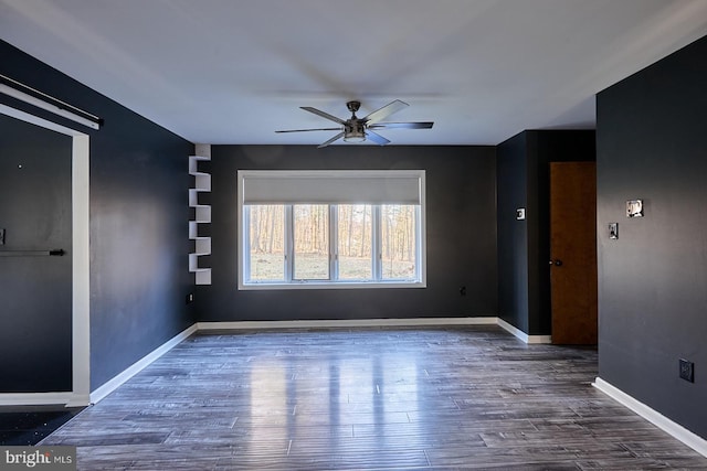 empty room featuring baseboards, wood finished floors, and a ceiling fan