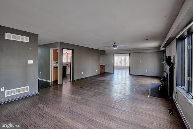 unfurnished living room featuring visible vents, baseboards, ceiling fan, and dark wood-style flooring