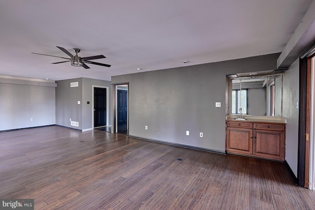 interior space with a sink, baseboards, dark wood-type flooring, and a ceiling fan