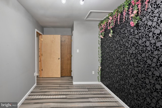 spare room featuring attic access, wood finished floors, and baseboards