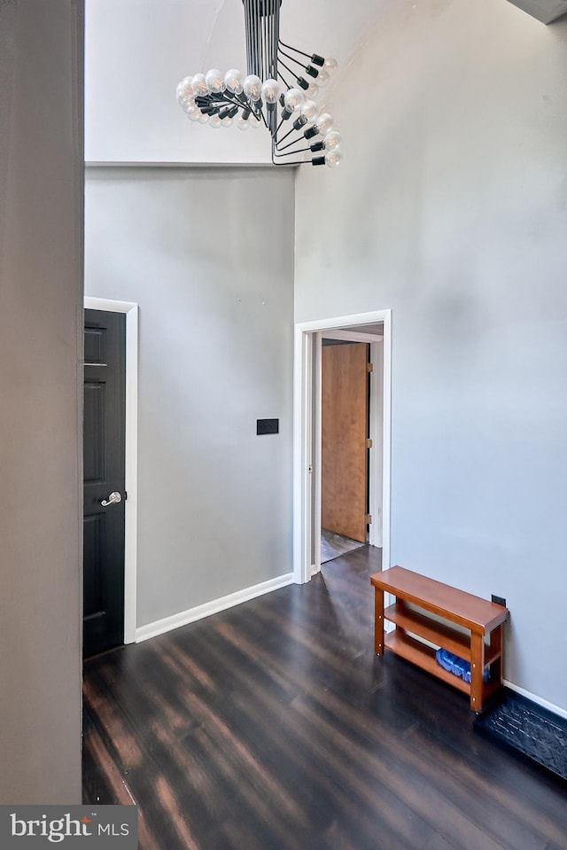 dining room with baseboards, a high ceiling, an inviting chandelier, and wood finished floors