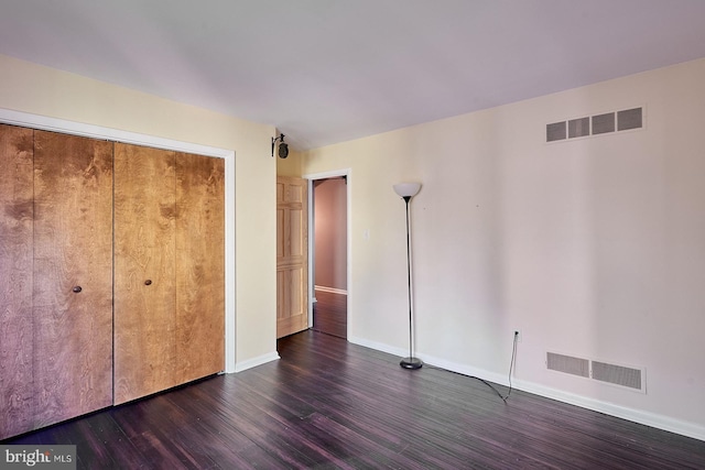 unfurnished bedroom featuring visible vents, baseboards, a closet, and dark wood-style flooring