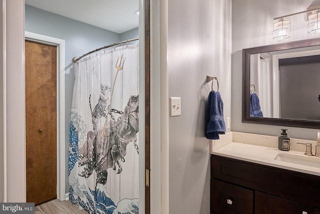 bathroom with curtained shower, vanity, and wood finished floors