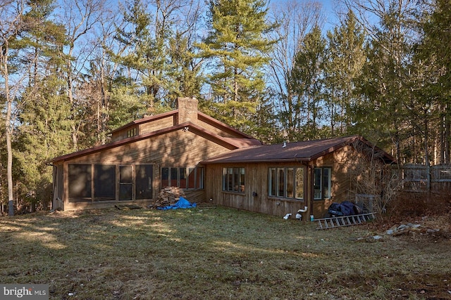 rear view of property with a lawn, a chimney, fence, and a sunroom