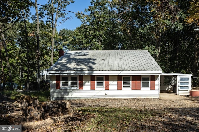 view of front facade with a carport, a chimney, and metal roof