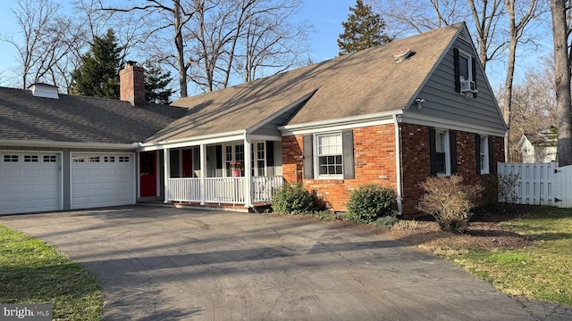 view of front of property featuring brick siding, aphalt driveway, covered porch, a chimney, and an attached garage