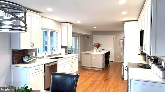 kitchen featuring stainless steel dishwasher, decorative backsplash, light wood-type flooring, and a sink