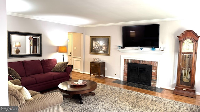 living area featuring baseboards, wood finished floors, a fireplace, and crown molding