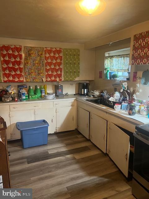 kitchen with light wood-type flooring, white cabinets, light countertops, and electric stove