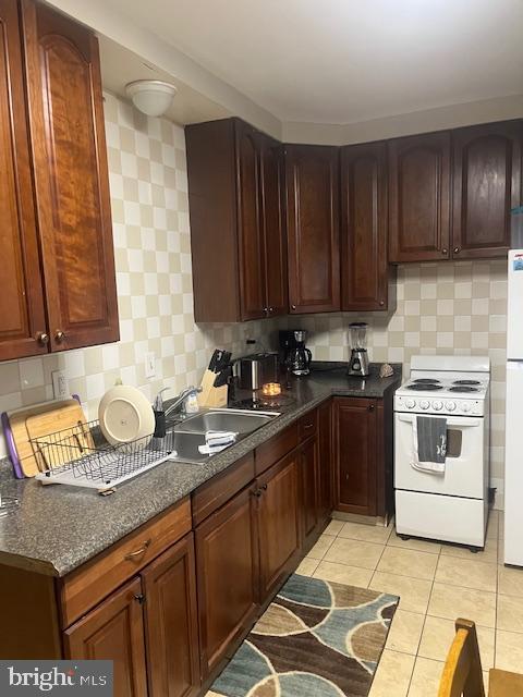 kitchen featuring light tile patterned floors, decorative backsplash, and white appliances