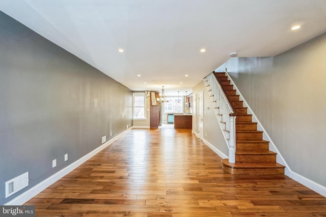 interior space featuring visible vents, baseboards, a chandelier, stairs, and hardwood / wood-style flooring