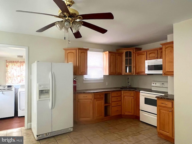 kitchen featuring dark countertops, glass insert cabinets, washing machine and dryer, white appliances, and a sink