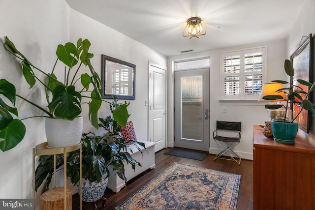 foyer with wood finished floors, visible vents, and baseboards