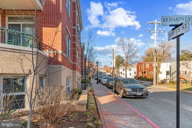 view of street featuring sidewalks, a residential view, curbs, and street lights