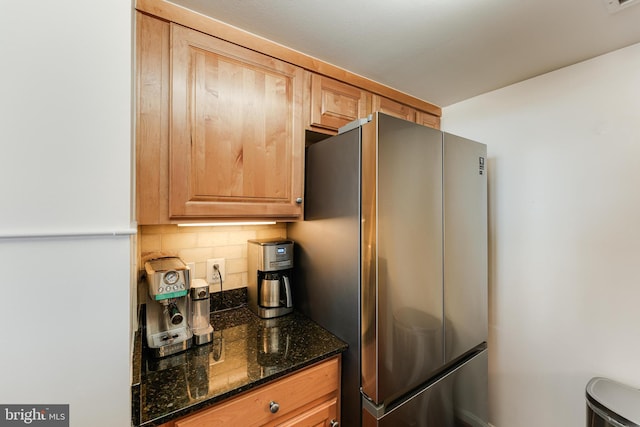 kitchen with decorative backsplash, dark stone countertops, visible vents, and freestanding refrigerator