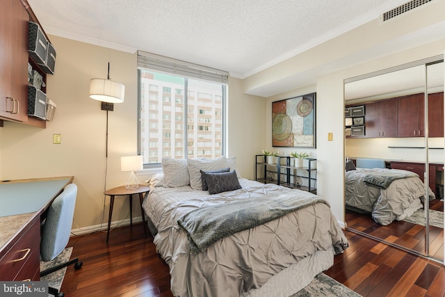 bedroom featuring visible vents, dark wood-type flooring, ornamental molding, and a textured ceiling