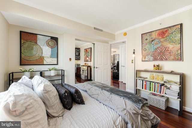 bedroom featuring ornamental molding, wood finished floors, visible vents, and baseboards