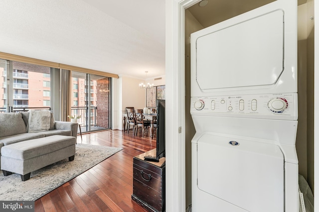 laundry area with a chandelier, laundry area, dark wood-type flooring, and stacked washer and dryer