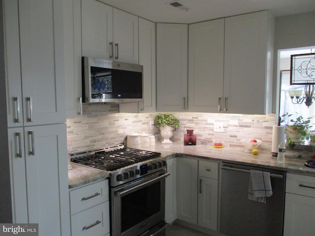 kitchen with light stone countertops, visible vents, appliances with stainless steel finishes, white cabinetry, and tasteful backsplash