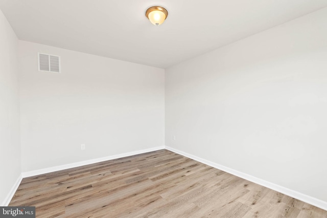 unfurnished room with wood finished floors, visible vents, and baseboards